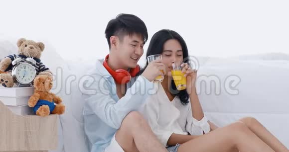 亚洲夫妇坐着喝橙汁视频的预览图