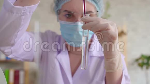 年轻女子将红色液体滴入试管中试管中有一个长长的玻璃吸管视频的预览图