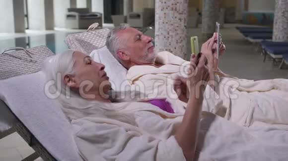 快乐的老夫妇使用电话放松酒店视频的预览图