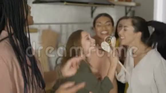 混合种族的5个朋友在厨房里玩得很开心女孩边跳边唱视频的预览图