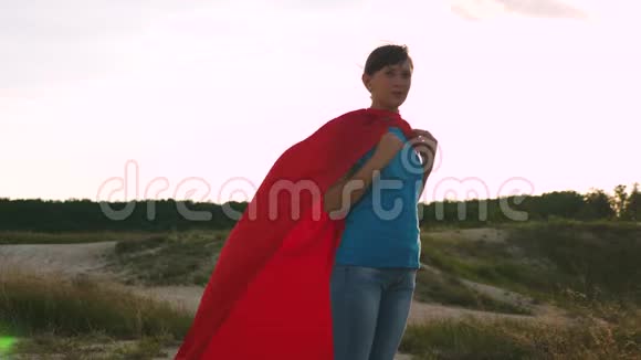 穿着红色雨衣的超级英雄女孩迎风微笑一个年轻女孩梦想成为超级英雄女孩走路视频的预览图