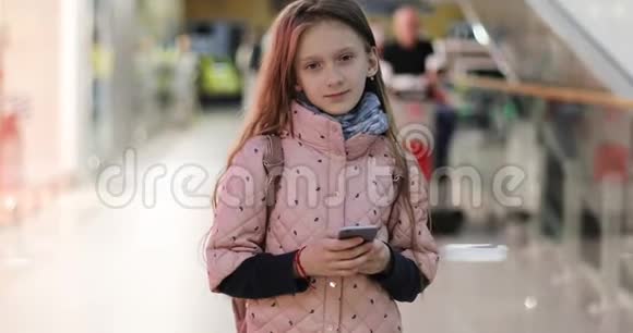可爱的带着手机的女学生站在商场里视频的预览图