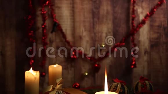 圣诞气氛一支前景有大火焰的蜡烛红色和金色的子脱钩的球缎子金丝带视频的预览图