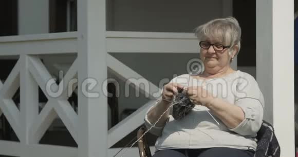 照顾年长的孙儿正把橘子汁带给老祖母她正在阳光D上一起编织和微笑视频的预览图