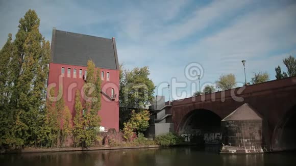 美丽的红高房子在河的对面一座古老的桥在池塘上视频的预览图