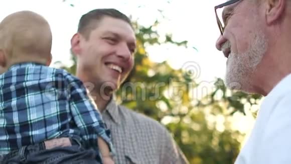 年轻人带着他的小儿子和年迈的父亲在公园散步幸福的家庭三代男人视频的预览图