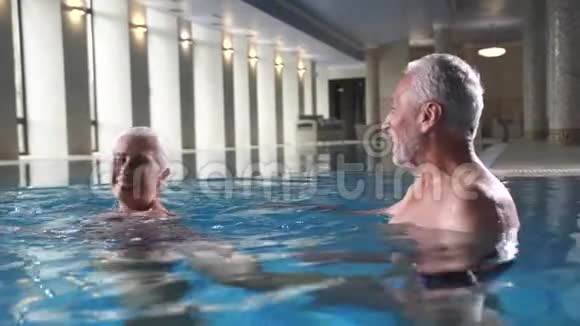 欢乐的老年夫妇在水疗酒店游泳池放松视频的预览图