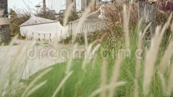 网眼复古时髦吊床挂在花园与高绿草在白天老式院子里的小穗子现代视频的预览图