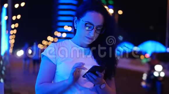 漂亮女人穿着白色T恤和眼镜站在街上用信用卡和智能手机在线支付视频的预览图