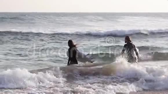 一对年轻的冲浪者正拿着冲浪板潜入大海视频的预览图