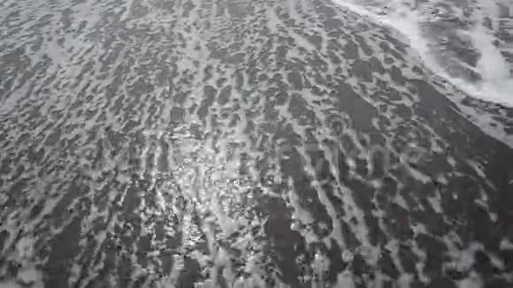 海边有波浪的沙滩太阳在水中反射沙滩上的沙子前景是海浪c上有泡沫的波浪视频的预览图