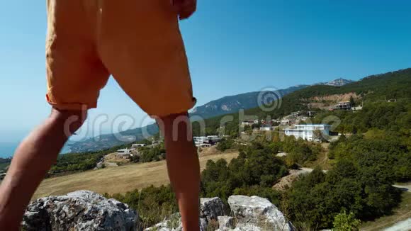 快乐的徒步旅行者站在山崖边缘天空和海洋背景和上升的手视频的预览图
