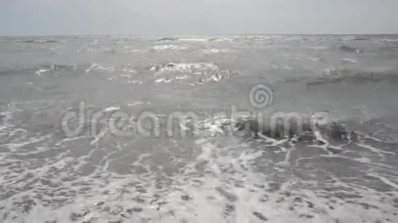 海边有波浪的沙滩太阳在水中反射沙滩上的沙子前景是海浪c上有泡沫的波浪视频的预览图