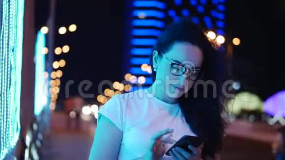 漂亮女人穿着白色T恤和眼镜站在街上用信用卡和智能手机在线支付视频的预览图