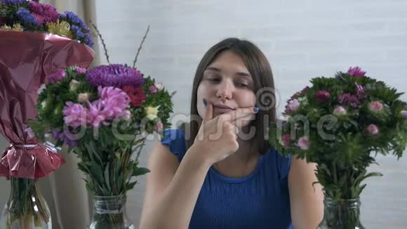 一位美丽而年轻的女士欣赏和闻到一束鲜花的特写肖像视频的预览图