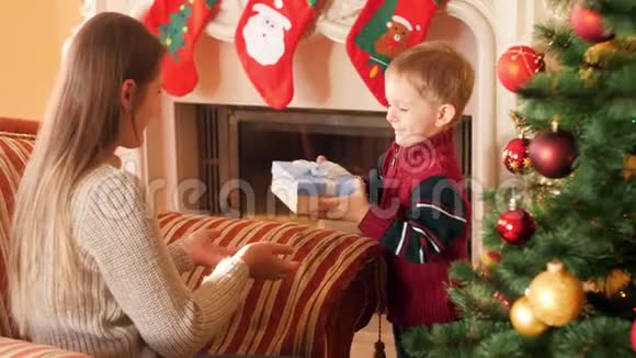 小男孩在圣诞节早上给他妈妈送礼物的4K镜头家庭捐赠和接受新年视频的预览图