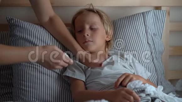 在床上生病的小男孩母亲用精油男孩的胸部涂抹药膏婴儿流感概念视频的预览图
