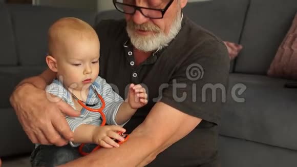 爷爷和孙子在家里一起休息的时候正在玩音响仪拥抱和微笑快乐视频的预览图