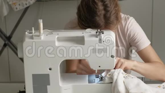一个女人在家庭作坊的缝纫机上缝衣服视频的预览图