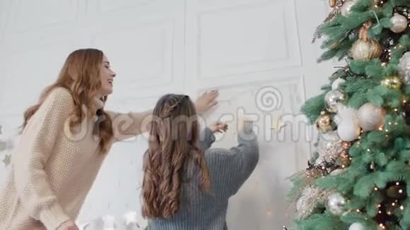 微笑的妈妈和十几岁的女儿把花环挂在客厅的墙上视频的预览图