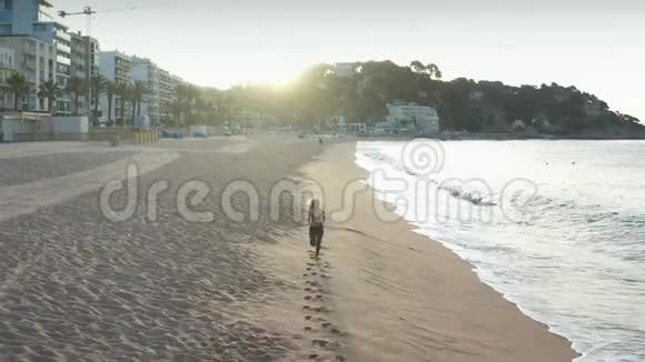 女性在海滩上快速奔跑的空中镜头视频的预览图