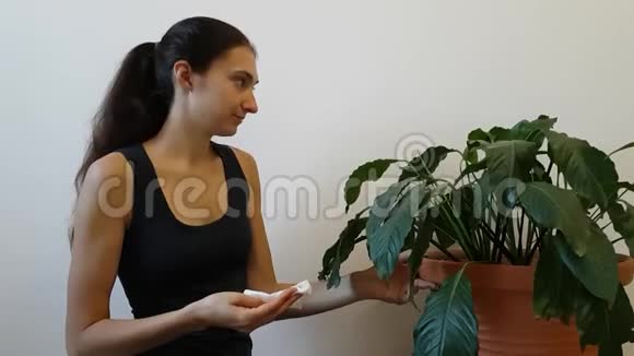 那个女孩在照料一盆花浸大植物的大叶一个女人微笑着转动一朵花视频的预览图