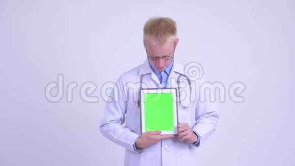 年轻的金发男医生在展示数码平板电脑时视频的预览图