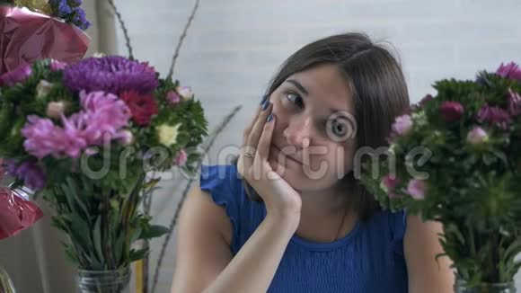 一位美丽而年轻的女士欣赏和闻到一束鲜花的特写肖像视频的预览图
