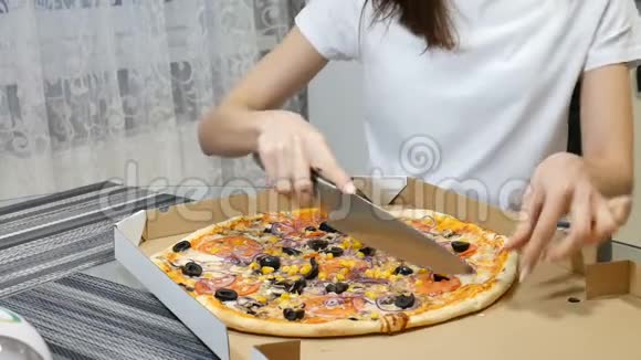女人用纸板盒切一个热比萨饼里面有蘑菇奶酪玉米橄榄红葱圈和西红柿视频的预览图