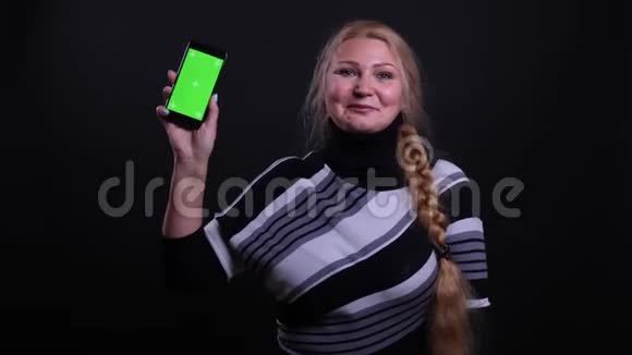用手机拍摄中年白种人女性的特写肖像并用背景镜头显示绿色屏幕视频的预览图