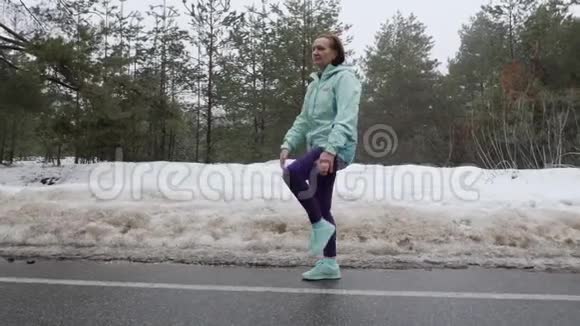 老白种人女人在雪地冬季公园跑步前热身侧射慢动作视频的预览图