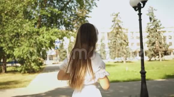 女孩带着耳机旅行听音乐微笑夏天的公园里欢快的女孩舞蹈视频的预览图