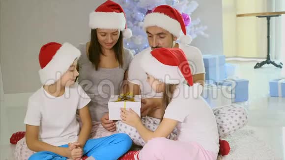 好奇的父母和兄弟姐妹打开一个圣诞礼物光来自里面视频的预览图