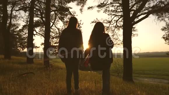 女孩在日落时携手穿过森林徒步旅行者女孩慢动作少女们正在散步视频的预览图