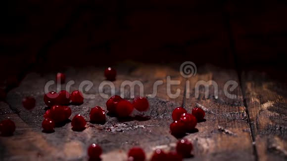 接近多汁的红色浆果落在黑色背景的深旧木桌上食物准备和视频的预览图