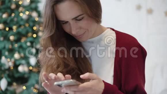严肃的女商人在圣诞节装饰的家中通过电话寻找礼物视频的预览图