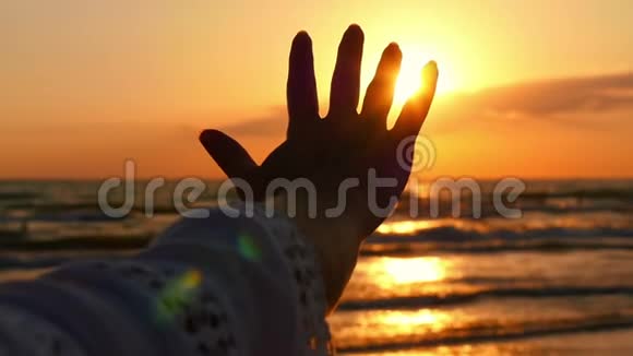 女孩手抚摸着阳光在大海日落的背景下视频的预览图