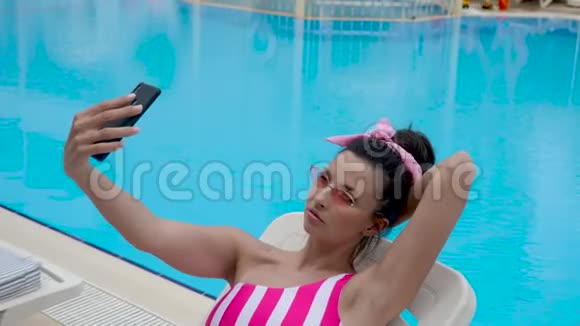 穿着条纹泳衣的女人穿着条纹泳衣躺在游泳池旁视频的预览图