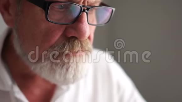 一个灰色的成熟男人戴着眼镜拿着笔记本电脑工作快乐晚年积极养老经营理念视频的预览图