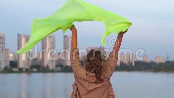 雪亮的女人在日落时分在大湖边跳着挥舞着她的透明帕雷奥视频的预览图