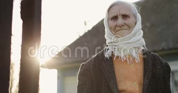 一位有着深深皱纹的老年妇女在美丽的日落背景上挥动她的手视频的预览图