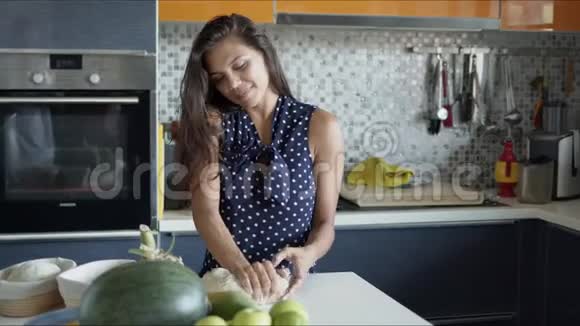 微笑的女人站在柜台前拿着产品在厨房揉面视频的预览图