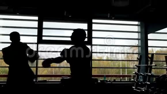 两个拳击手在窗户前的一个黑暗的房间里打架的剪影库存录像侧视视频的预览图