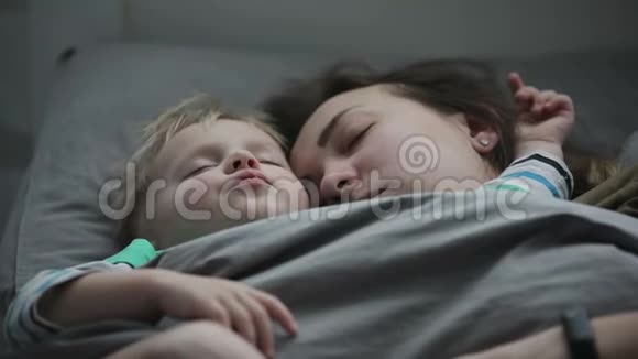 妈妈和宝宝一起午睡一个年轻的女人和她的小儿子睡在床上视频的预览图