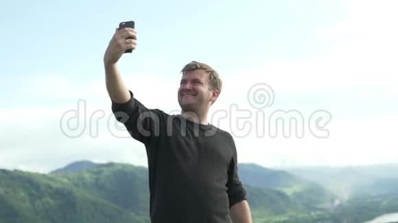 一个英俊的男人在手机上自拍背景是阿尔泰山视频的预览图