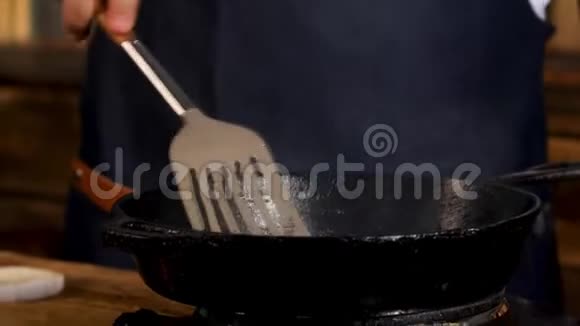 用黑色铁锅将男厨炒制的食材合上用金属铲子搅拌库存录像流程视频的预览图