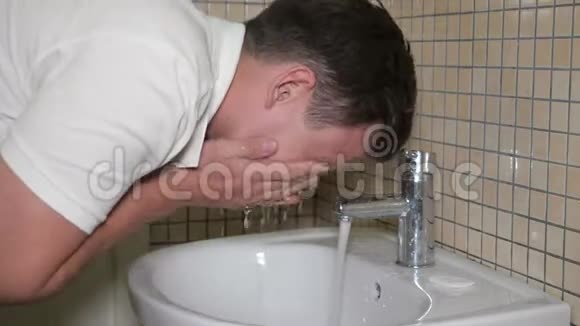 年轻人正在浴室的小水槽里洗脸侧视视频的预览图