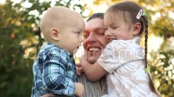 幸福的年轻父亲牵着他的两个孩子一个儿子和一个女儿一个男孩和一个女孩美丽的家庭视频的预览图