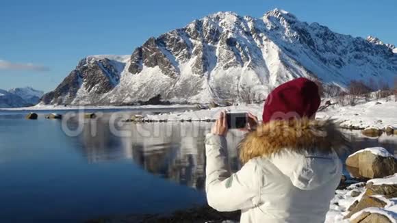 女孩在阳光明媚的冬季峡湾拍照视频的预览图