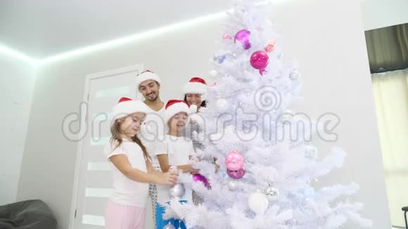 四个家庭成员穿着睡衣和圣诞帽准备圣诞树寒假视频的预览图